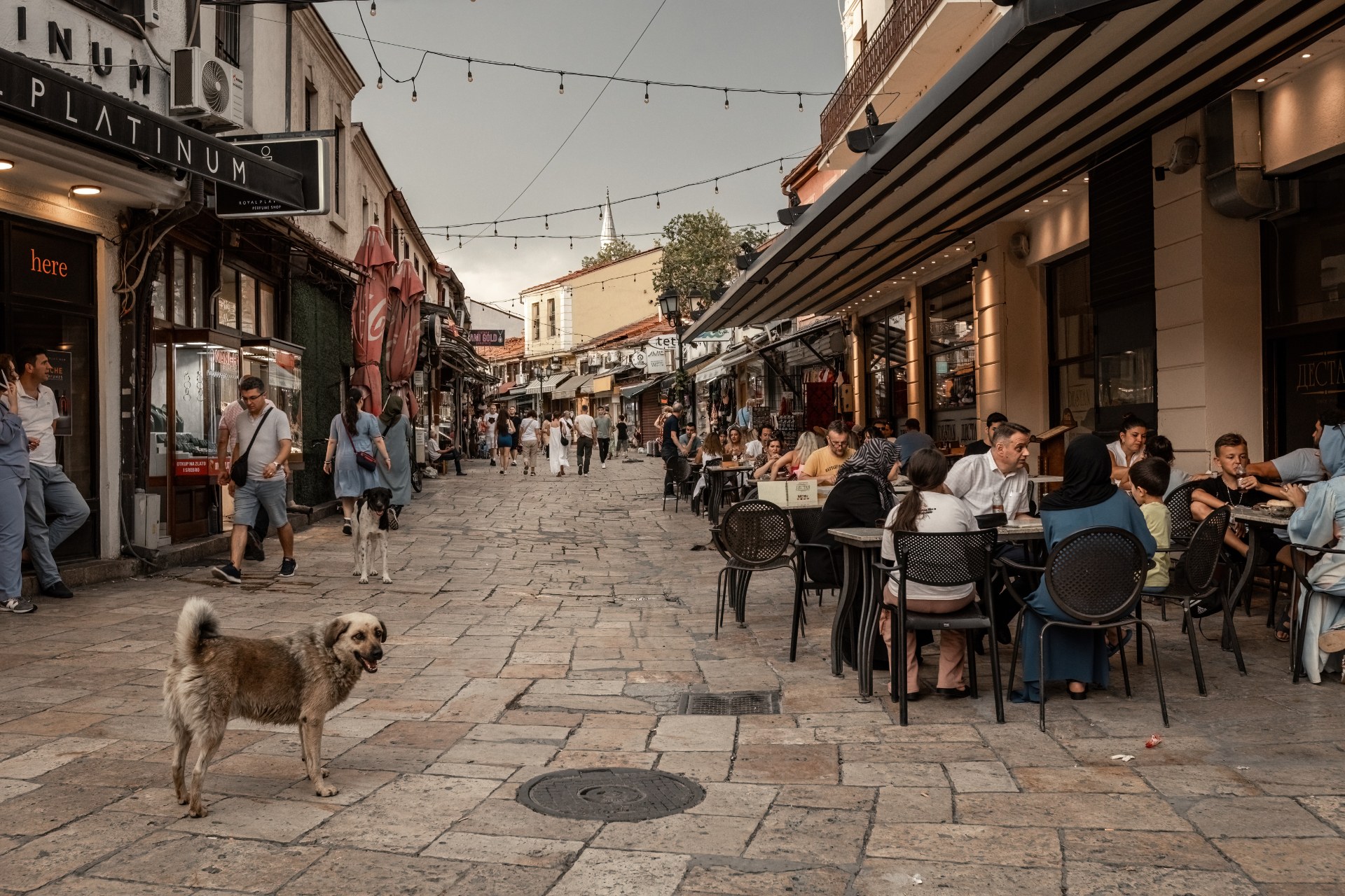 Pessoas nas esplanadas de uma rua estreita do mercado, no centro histórico de Escópia